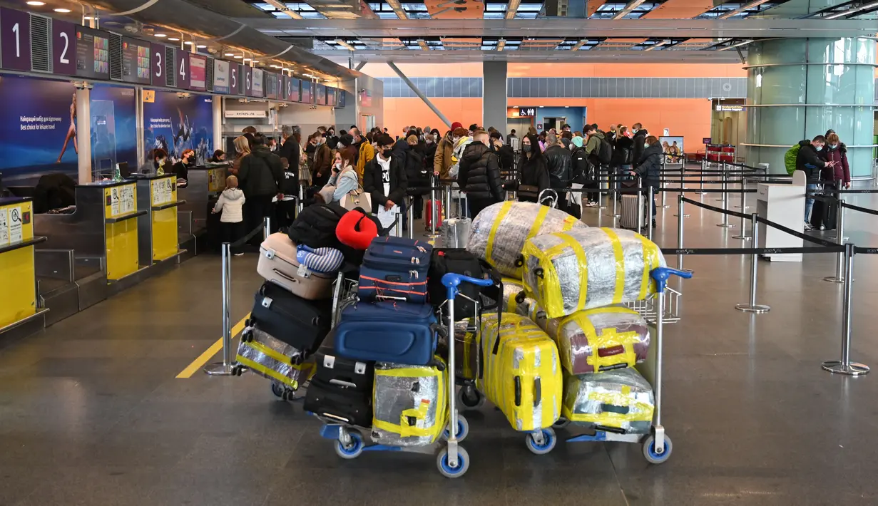 Pelancong menunggu di konter check-in sebelum penerbangan mereka di bandara Boryspil, luar Kiev, 13 Februari 2022. Ukraina berjanji menjaga wilayah udaranya terbuka untuk perjalanan internasional setelah negara Barat memperingatkan pasukan Rusia dapat menyerang kapan saja. (Sergei Supinsky/AFP)