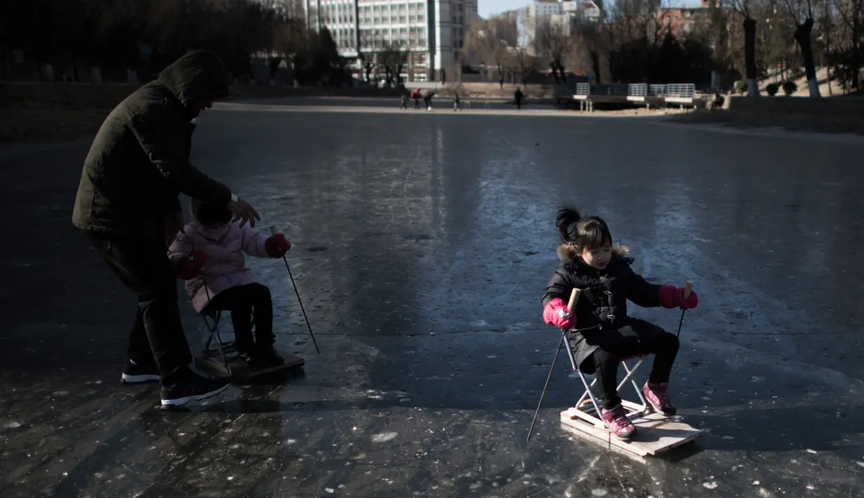 Sejumlah anak bermain di sungai yang membeku di Beijing, China (21/1). Akibat membeku, Sungai ini menjadi objek wisata dadakan yang banyak diminati wisatawan. (AFP/Fred Dufour)