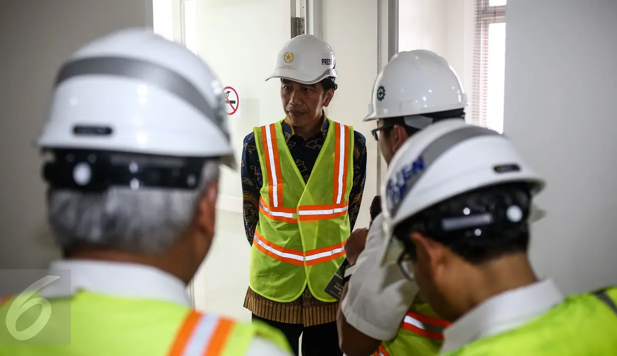 Presiden Jokowi mendengarkan paparan progres pembangunan Wisma Atlet usai meresmikan pengecoran akhir atap atau topping off di Kemayoran, Jakarta, Kamis (29/12). Pembangunan rusun ini memakan biaya Rp 3,4 triliun. (Liputan6.com/Faizal Fanani)
