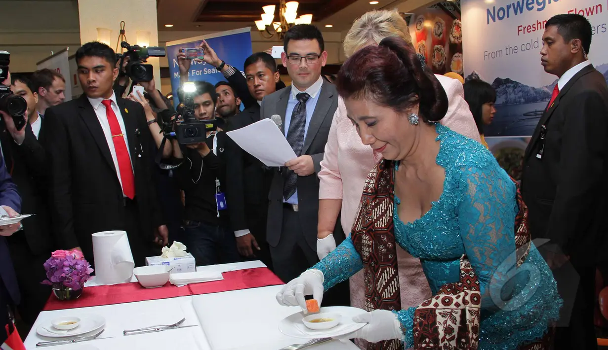 Menteri Kelautan dan Perikanan Susi Pudjiastuti (kanan) secara simbolis memakan salmon usai penandatangan kerjasama dengan pemerintah Norwegia dalam bidang kelautan dan perikanan di Jakarta, Selasa (14/4/2015). (Liputan6.com/Helmi Afandi)