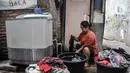 Warga mencuci pakaian menggunakan air tampungan di Kampung Baru Kubur, Penjaringan, Jakarta Utara, Selasa (11/1/2022). Krisis air bersih memaksa warga membeli air dari pedagang keliling dan kemudian ditampung dalam drum atau bak. (merdeka.com/Iqbal S. Nugroho)