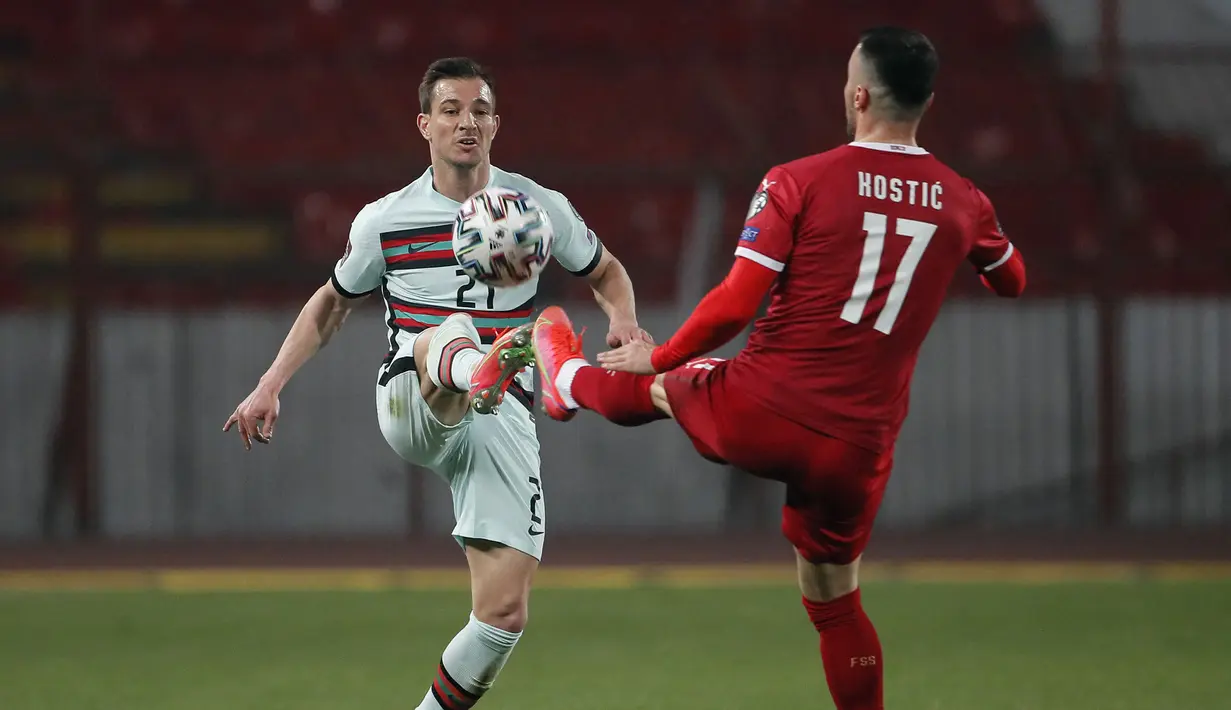 Bek Portugal, Cedric Soares (kiri) berebut bola dengan gelandang Serbia, Filip Kostic dalam laga Kualifikasi Piala Dunia 2022 Zona Eropa Grup A di Rajko Mitic Stadum, Belgrade, Sabtu (27/3/2021). Portugal bermain imbang 2-2 dengan Serbia. (AFP/Pedja Milosavljevic)