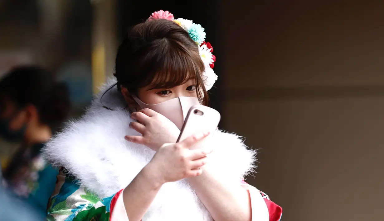 Seorang wanita berusia 20 tahun mengenakan kimono menunggu di pintu masuk Todoroki Arena untuk menghadiri upacara perayaan "Coming-of-Age Day" di Kawasaki, prefektur Kanagawa (11/1/2021). Acara ini digelar dalam keadaan darurat karena Covid-19 pandemi virus corona. (AFP/Behrouz Mehri)