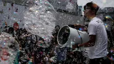 Seorang petugas meniupkan angin pada gelembung selama pertunjukan seni Bubble Up yang dibuat oleh seniman asal Jepang Shinji Ohmaki, di Hong Kong, 2 Agustus 2017. (AP Photo/Kin Cheung)