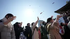 Orang-orang mencoba menangkap kacang keberuntungan yang disebarkan pada "Mame-maki," upacara pelemparan kacang di kuil Buddha Zojoji di Tokyo, 3 Februari 2022. Ritual yang diyakini membawa keberuntungan dan mengusir kejahatan dilakukan setiap tahun untuk menandai awal musim semi. (AP/Eugene Hoshiko)