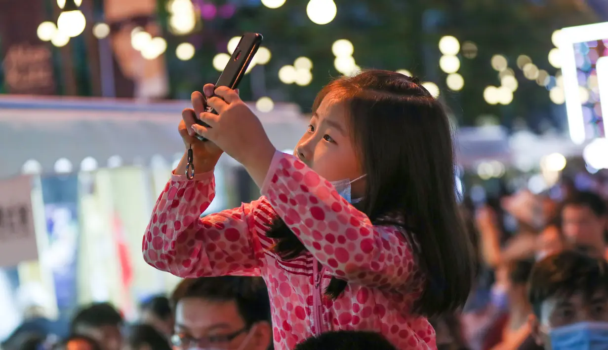 Seorang anak mengambil foto di sebuah pasar malam di Shanghai, China timur (6/6/2020). Sejumlah bar, museum, toko buku, pusat perbelanjaan, dan kompleks komersial besar ikut serta dalam festival itu dengan jam operasional yang diperpanjang. (Xinhua/Ding Ting)