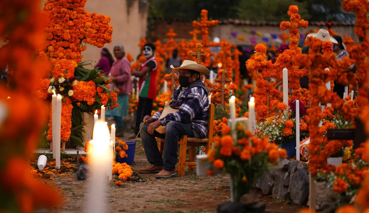 Kerabat bersiap untuk bermalam di samping makam tercinta pada perayaan Hari Kematian di pemakaman Arocutin, Michoacan, Meksiko, 1 November 2021. Tradisi ini bertepatan dengan Hari Semua Orang Kudus dan Hari Semua Jiwa. (AP Photo/Eduardo Verdugo)