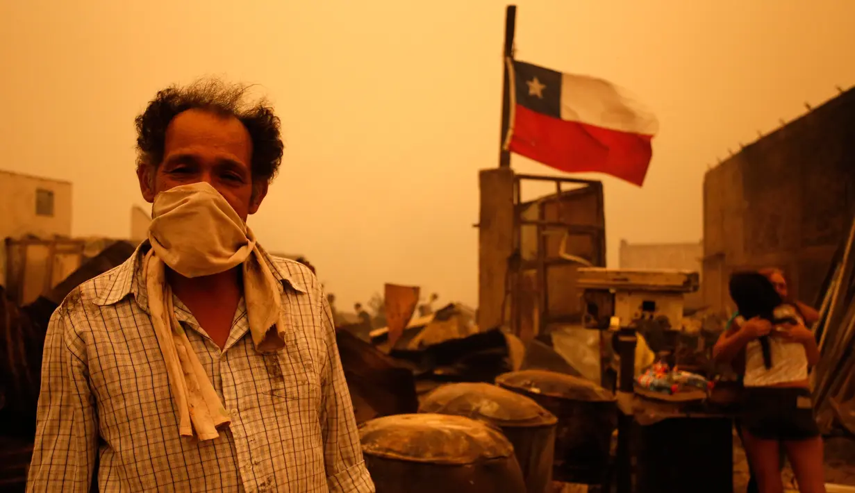 Warga berdiri menggunakan masker selama kebakaran hutan di Santa Olga, Chile, (26/1). Chile dilanda kebakaran hutan terbesar yang menghanguskan ratusan rumah, sejumlah fasilitas umum, dan juga sekolah. (Javier Torres/Aton via AP)