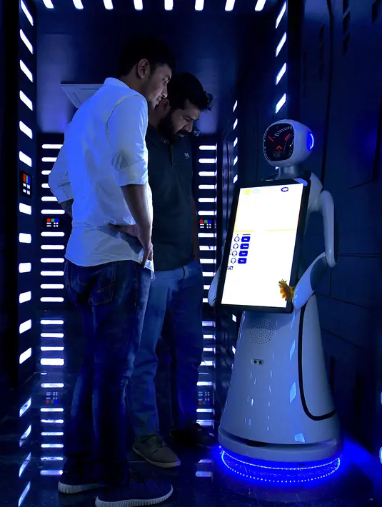 Pelanggan memeriksa robot Android interaktif saat pembukaan restoran di Bangalore, India, Sabtu (17/8/2019). Setiap meja dilengkapi dengan tablet di mana pengunjung dapat memesan dan memanggil robot. (Manjunath Kiran/AFP)