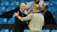 Pelatih Real Madrid, Zinedine Zidane berjabat tangan dengan manajer Manchester City, Pep Guardiola di Etihad Stadium pada leg kedua 16 besar Liga Champions 2019/2020, Sabtu (8/8/2020). (AFP/Peter Powell)