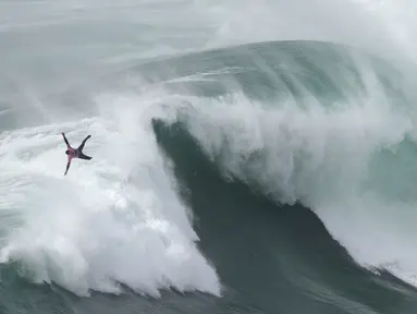 Peselancar Eric Rebiere dari Prancis mengudara keluar dari ombak selama kompetisi selancar ombak besar Nazare Tow Challenge di Praia do Norte, atau Pantai Utara, di Nazare, Portugal, 10 Februari 2022. (AP Photo/Armando Franca)