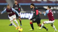 Penyerang Liverpool, Mohamed Salah, berebut bola dengan pemain West Ham United, Aaron Cresswell, pada laga Liga Inggris di Stadion London, Minggu (31/1/2021). Liverpool menang dengan skor 3-1. (Clive Rose/Pool via AP)