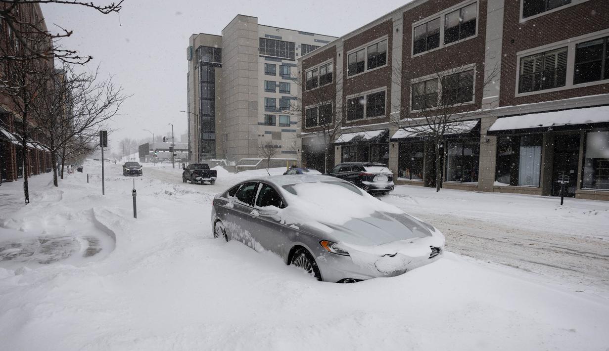 Sebuah mobil terkubur dalam salju selama badai salju di lingkungan East Village di Des Moines, Iowa, pada tanggal 12 Januari 2024. (Christian MONTERROSA/AFP)