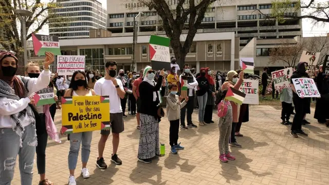 Peserta aksi protes di Saskatoon sambil memegang papan bertuliskan dukungan bagi Palestina di depan balai kota. (Tyler Barrow / CTV News Saskatoon)