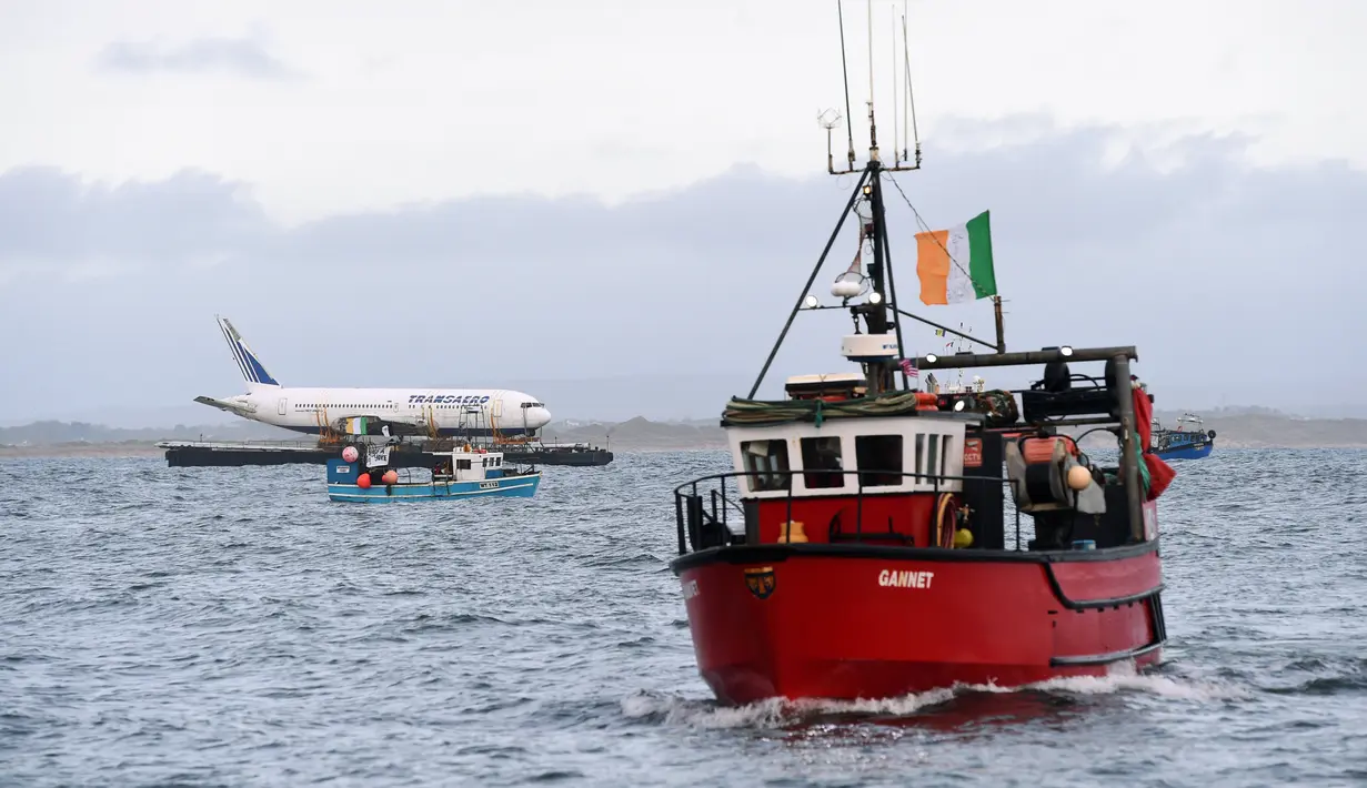 Kapal tugboat yang menarik tongkang bermuatan Boeing 767 tiba di muara Enniscrone, pantai barat Irlandia, Sabtu (7/5). Pesawat yang dibeli seharga £16,000 itu dipindahkan dari landasan pacu di Bandara Shannon ke Knockbeg Point. (REUTERS/Clodagh Kilcoyne)