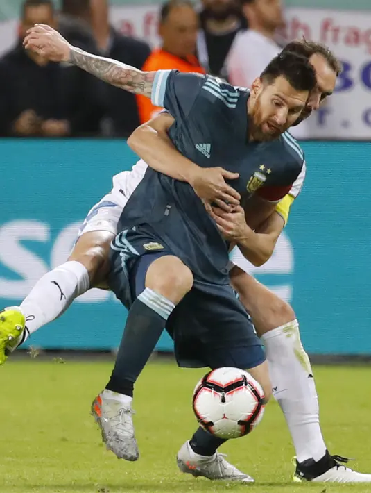 Megabintang timnas Argentina, Lionel Messi berebut bola dengan bek Uruguay Diego Godin dalam laga persahabatan di Stadion Bloomfield, Tel Aviv, Israel, Senin (18/11/2019). Skor berakhir 2-2, dengan penalti Lionel Messi menghindarkan timnas Argentina  dari kekalahan. (Jack GUEZ/AFP)