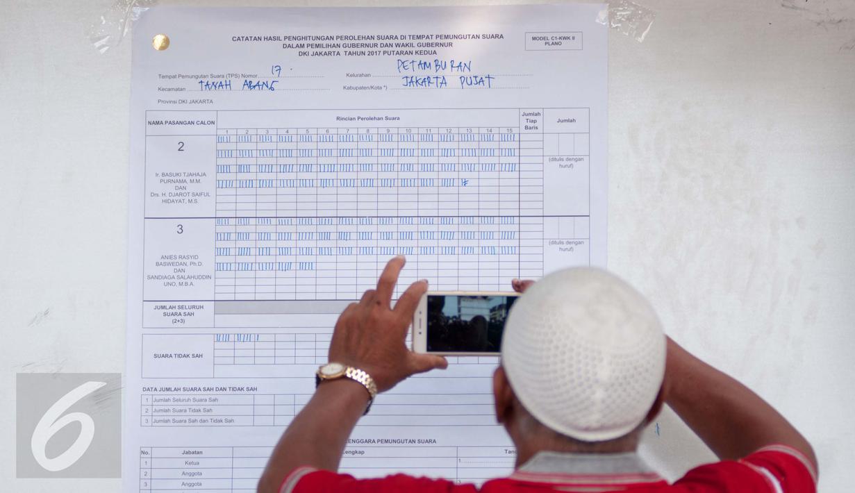 Petugas mengambil gambar hasil perhitungan suara Pilkada DKI 2017 di TPS 17, Petamburan, Tanah Abang, Jakarta, Rabu (19/4). Pasangan nomor urut 2, Ahok-Djarot unggul tipis dari pasangan nomor 3, Anies-Sandi. (Liputan6.com/Gempur M Surya)