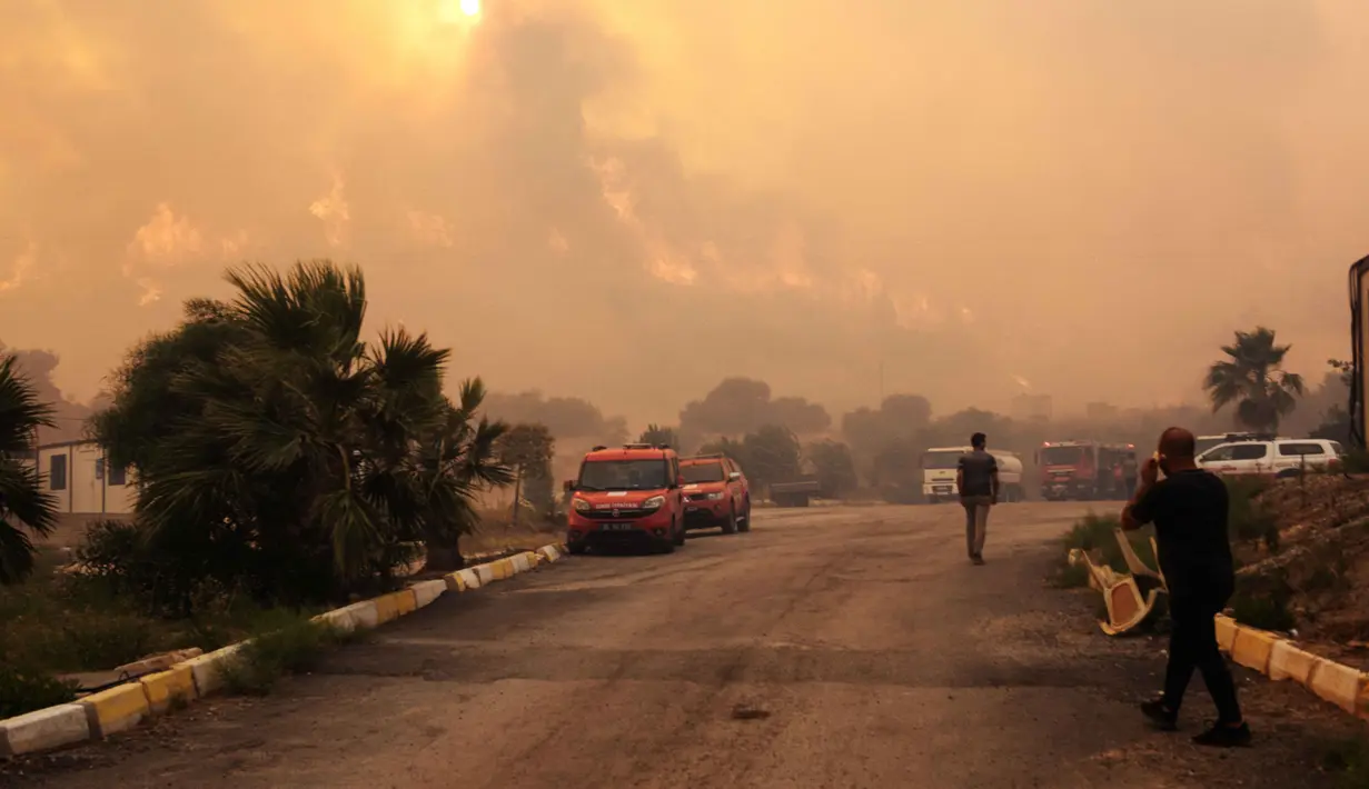 Warga dan petugas pemadam kebakaran berusaha memadamkan api saat asap dan kobaran api membumbung tinggi dari sebuah kawasan hutan menyusul kebakaran hutan di distrik Seferihisar, Izmir, Turki, pada 30 Juni 2025. (Ahmet Ayberk Cimen/AFP)