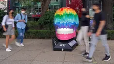 Orang-orang melewati tengkorak yang dihias selama pameran edisi keempat "Mexicraneos" (Mexisculls) di Reforma Avenue, Mexico City pada 23 Oktober 2020. Instalasi sebanyak 55 tengkorak berbagai warna tersebut menghiasi jalanan sebagai bagian dari perayaan Day of the Dead. (ALFREDO ESTRELLA/AFP)