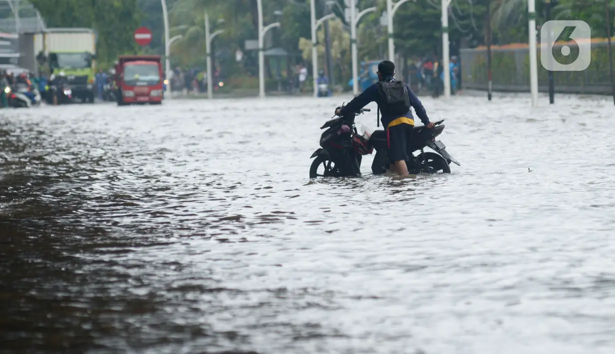 Pengendara mendorong sepeda motor mereka saat melewati banjir yang merendam Jalan Ahmad Yani, Jakarta, Sabtu (8/2/2020). Hujan yang mengguyur Jakarta sejak semalam membuat sejumlah ruas jalan terendam banjir. (merdeka.com/Imam Buhori)