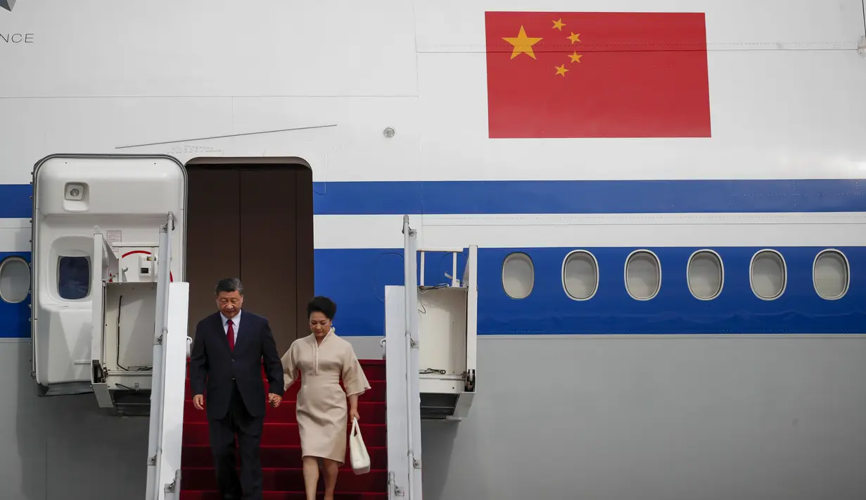 Presiden China Xi Jinping dan istrinya Peng Liyuan saat turun dari pesawat setibanya di Bandara Internasional Ngurah Rai menjelang KTT G20 di Bali, Senin (14/11/2022). Pengawalan ketat mengiringi kedatangan Presiden China, Xi Jinping. Selain pasukan pengamanan yang disiapkan oleh Indonesia, Presiden Xi Jinping juga diiringi pasukan kepercayaan dari negera Tirai Bambu ini. (Ajeng Dinar Ulfiana/Pool Photo via AP)