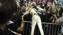 Pebalap Mercedes, Lewis Hamilton merayakan kemenangan bersama awak tim pada balapan F1 Singapura di Marina Bay City Circuit Singapore,(17/9/2017). (AP/Yong Teck Lim)
