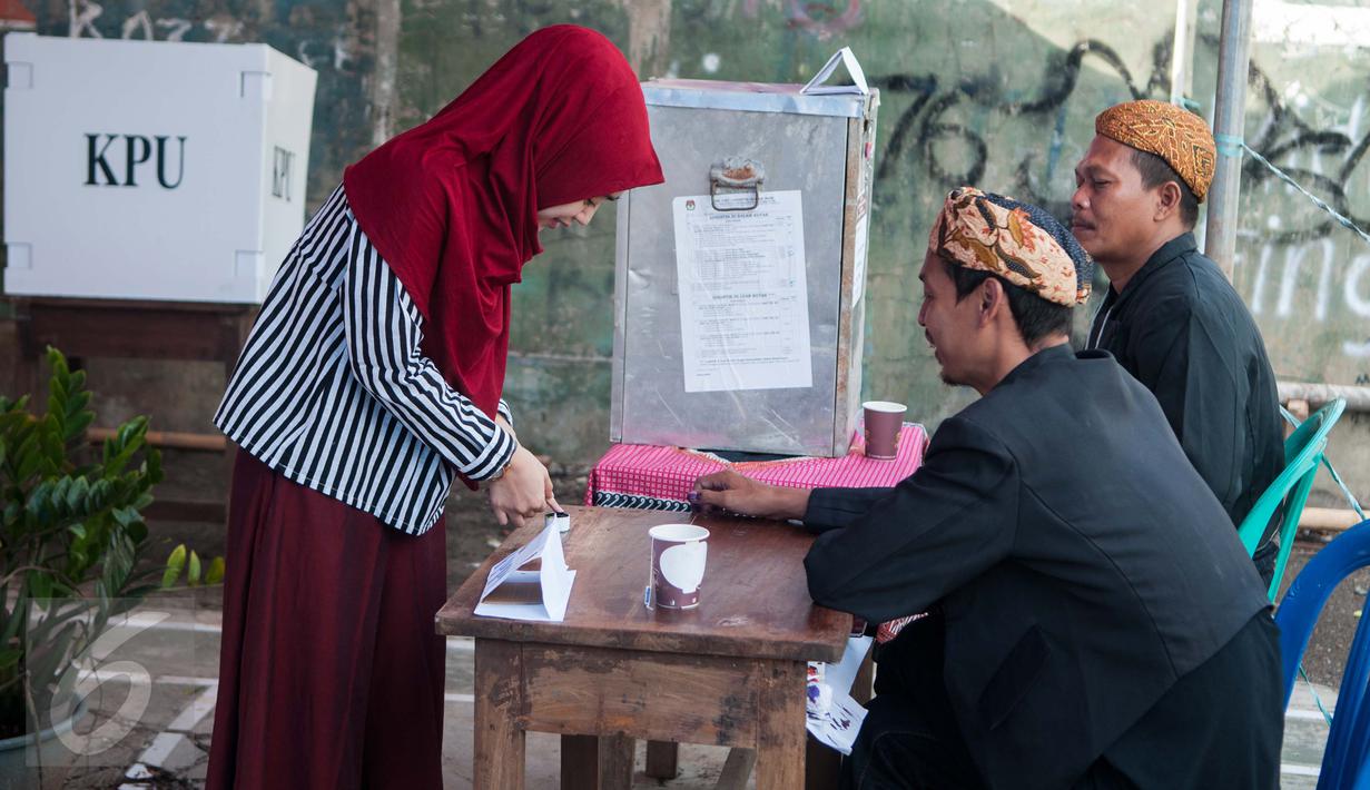 Petugas KPPS mengenakan pakaian adat dan belangkon memberikan pelayanan kepada warga yang menggunakan hak pilih di TPS 14 Cipinang Besar Selatan, Jakarta, Rabu (19/4). (Liputan6.com/Gempur M. Surya)