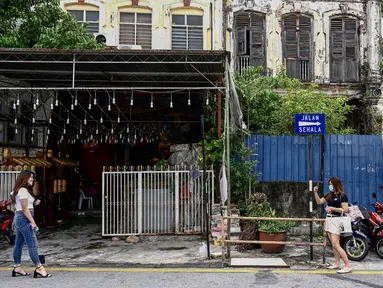 Turis lokal mengambil foto di sepanjang kawasan tua di Penang (1/8/2020). Malaysia tengah memperingatkan gelombang kedua virus corona COVID-19. (AFP Photo/Goh Chai Hin)