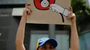Seorang dokter muda membawa poster bertuliskan "You are killing us," saat unjuk rasa menuntut Presiden Venezuela Nicolas Maduro di Caracas, Venezuela, (22/5). Sedikitnya 46 orang telah meninggal dunia. (AP Photo/Ariana Cubillos)