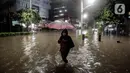 Warga mengunakan payung melintasi banjir di Jalan Kemang Raya, Jakarta Selatan, Selasa (4/10/2022). Hujan yang mengguyur wilayah Ibu Kota Jakarta mengakibatkan banjir menggenangi kawasan Kemang, Jakarta. (Liputan6.com/Johan Tallo)