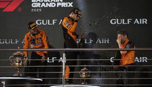 Juara F1 GP Bahrain 2025, Oscar Piastri (kiri), bersama rekan setimnya yang menempati podium ketiga, Lando Norris (tengah), dan team principal McLaren, Andrea Stella, merayakan keberhasilan tim di podium GP Bahrain, di Sirkuit Sakhir, Minggu (13/4/2025) malam WIB. (AP Photo/Altaf Qadri)