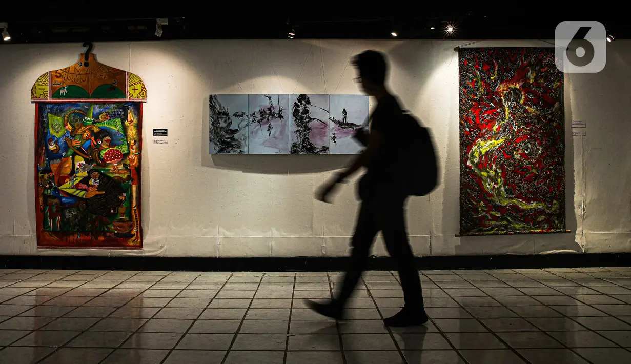 Pengunjung melewati lukisan yang ditampilkan dalam pameran bertajuk "Hai, Kamu!" di Balai Budaya, Jakarta, Kamis (4/11/2021). Pameran untuk mengenang penyair WS Rendra (1935-2009) ini menampilkan 19 karya dari 15 pelukis yang terinspirasi dari karya puisi WS Rendra. (Liputan6.com/Faizal Fanani)