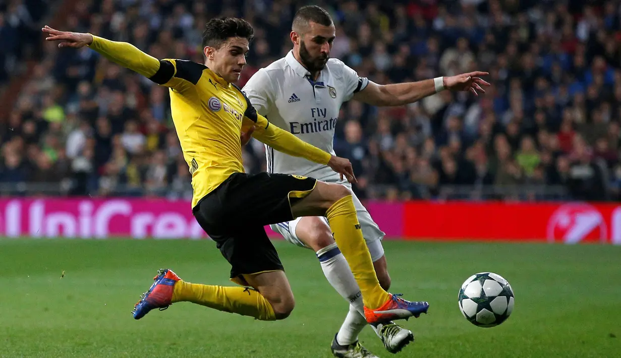 Penyerang Real Madrid, Karim Benzema berusaha melewati bek Marc Bartra pada pertandingan Grup F Liga Champions di Santiago Bernabeu, Madrid, (8/12). Real Madrid bermain imbang 2-2 dengan Dortmund. (REUTERS/Juan Medina)