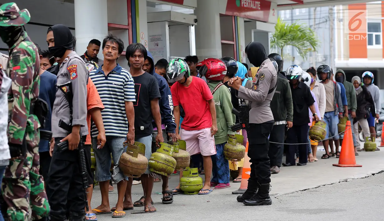 Aparat polisi menjaga antrean operasi pasar elpiji di SPBU Ki Hajar Dewantara di Palu, Sulawesi Tengah, Senin (8/10). Pertamina melakukan operasi pasar elpiji pascagempa dan tsunami Palu di 16 titik di Palu, Donggala dan Sigi (Liputan6.com/Fery Pradolo)