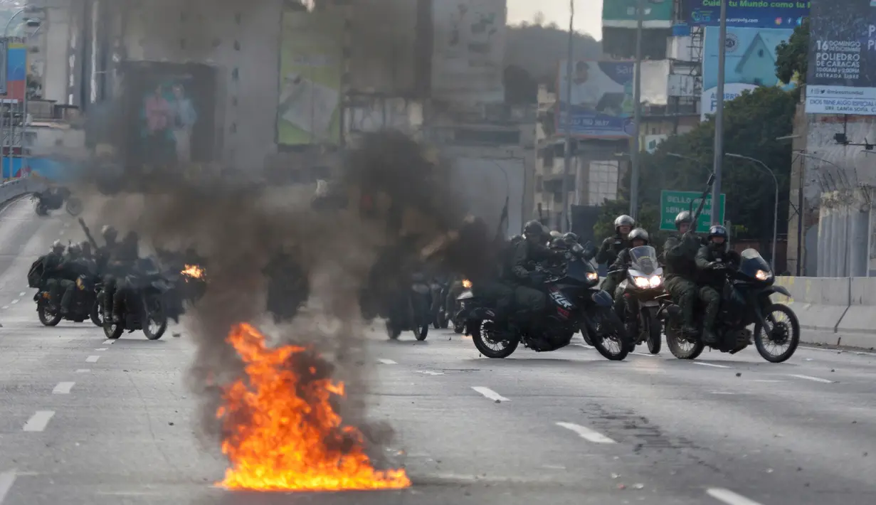 Pengawal Nasional Bolivarian Venezuela menembakkan peluru karet ke sekelompok kecil pemrotes antipemerintah ketika mereka mencoba memblokir jalan di Caracas, Venezuela, Sabtu (2/2). (AP Photo/Fernando Llano) (AP Photo/Juan Carlos Hernandez)