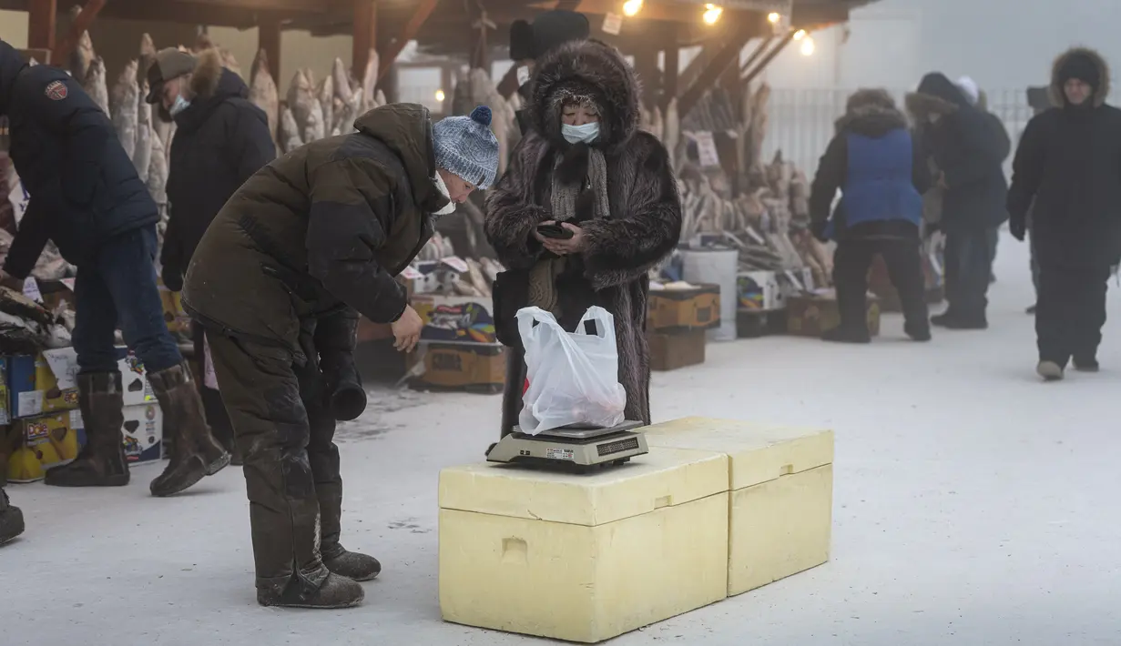 Orang-orang membeli ikan beku di pasar jalanan saat suhu turun hingga sekitar minus 50 derajat Celcius (-58 derajat Fahrenheit) di Yakutsk, Rusia, Sabtu (16/1/2021).  Yakutsk atau Yakutia tersohor sebagai kota terdingin di dunia. (AP Photo/Tatiana Gasich)