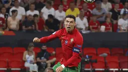 Pemain Portugal Cristiano Ronaldo menyundul bola di atas pemain Prancis Presnel Kimpembe pada pertandingan Grup F Euro 2020 di Puskas Arena, Budapest, Hungaria, Rabu (23/6/2021). Laga berakhir imbang 2-2. (Bernadett Szabo, Pool photo via AP)