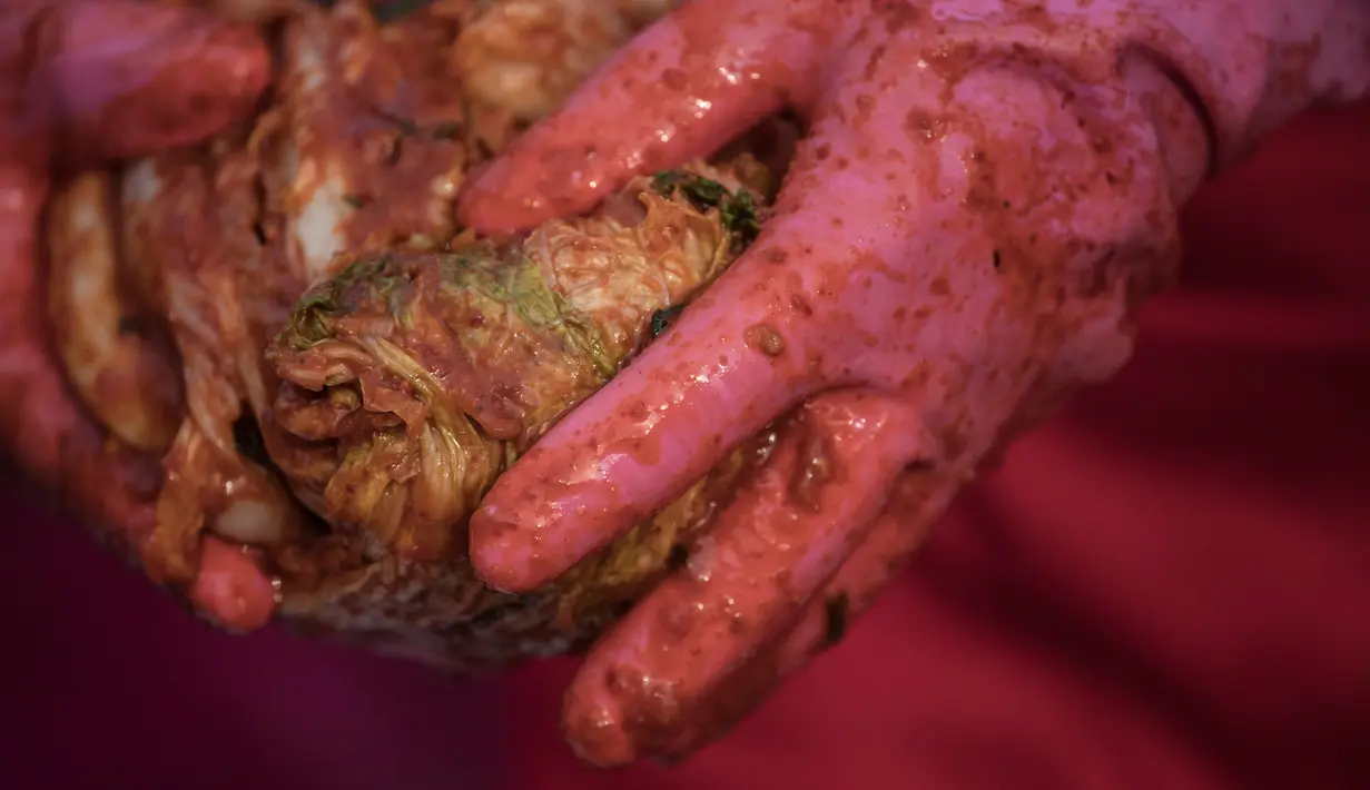 Seorang peserta memegang kimchi, hidangan tradisional Korea Selatan, selama Festival Kimchi tahunan di pusat kota Seoul, Jumat (3/11). Acara tersebut dibuat oleh para sukarelawan yang hasilnya didonasikan untuk kaum minoritas. (Ed JONES/AFP)