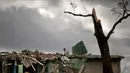 Seorang pria mencari barang miliknya di sebuah bangunan yang hancur dihantam badai tornado di Regla, Kuba (28/1). Hantaman tornado mengakibatkan rumah-rumah hancur berantakan, mobil bergelimpangan hingga pepohonan tumbang. (AP Photo/Ramon Espinosa)