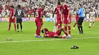 Pemain Qatar, Salem Al Hajri, terbaring karena terkena lemparan sebuah benda saat menghadapi Uni Emirat Arab pada semifinal Piala Asia 2019. Pada laga itu, Qatar menang 2-0 atas UEA. (AFP/Guiseppe Cacace)