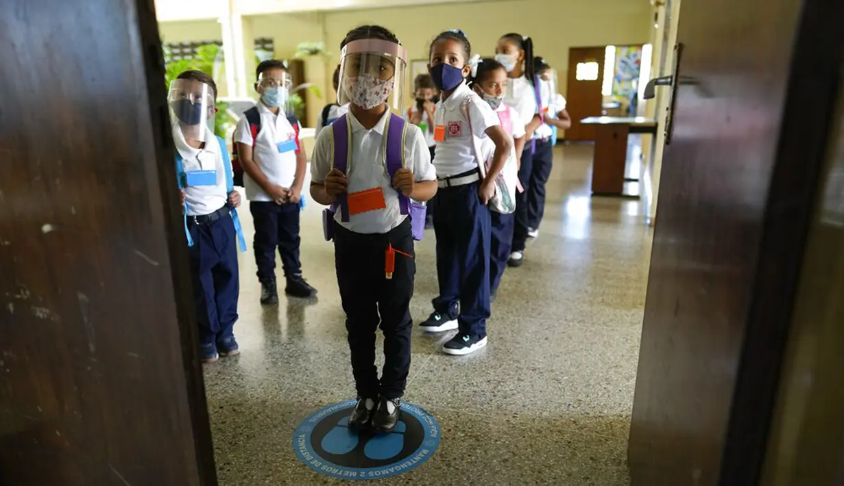 Para siswa menunggu instruksi untuk masuk ruang kelas pada hari pertama kembali ke kelas tatap muka sejak dimulainya pembatasan pandemi COVID-19 di sebuah sekolah umum di Caracas, Venezuela, 25 Oktober 2021. (AP Photo/Ariana Cubillos)