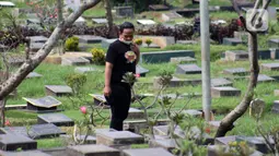 Peziarah mencari makam kerabatnya di Tempat Pemakaman Umum Karet Bivak, Jakarta, Sabtu (18/4/2020). Selama masa PSBB, peziarah yang memasuki kawasan TPU dibatasi dan diwajibkan menggunakan masker sebagai langkah pencegahan penyebaran virus Covid-19. (Liputan6.com/Helmi Fithriansyah)