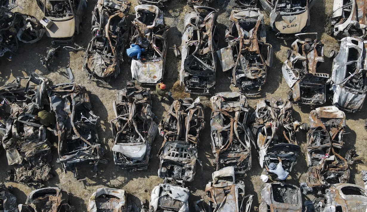 Pasukan keamanan Israel memeriksa kendaraan hangus yang terbakar dalam serangan berdarah lintas perbatasan pada 7 Oktober oleh militan Hamas, di luar kota Netivot, Israel selatan, Rabu (1/11/2023). (AP Photo/Ariel Schalit)