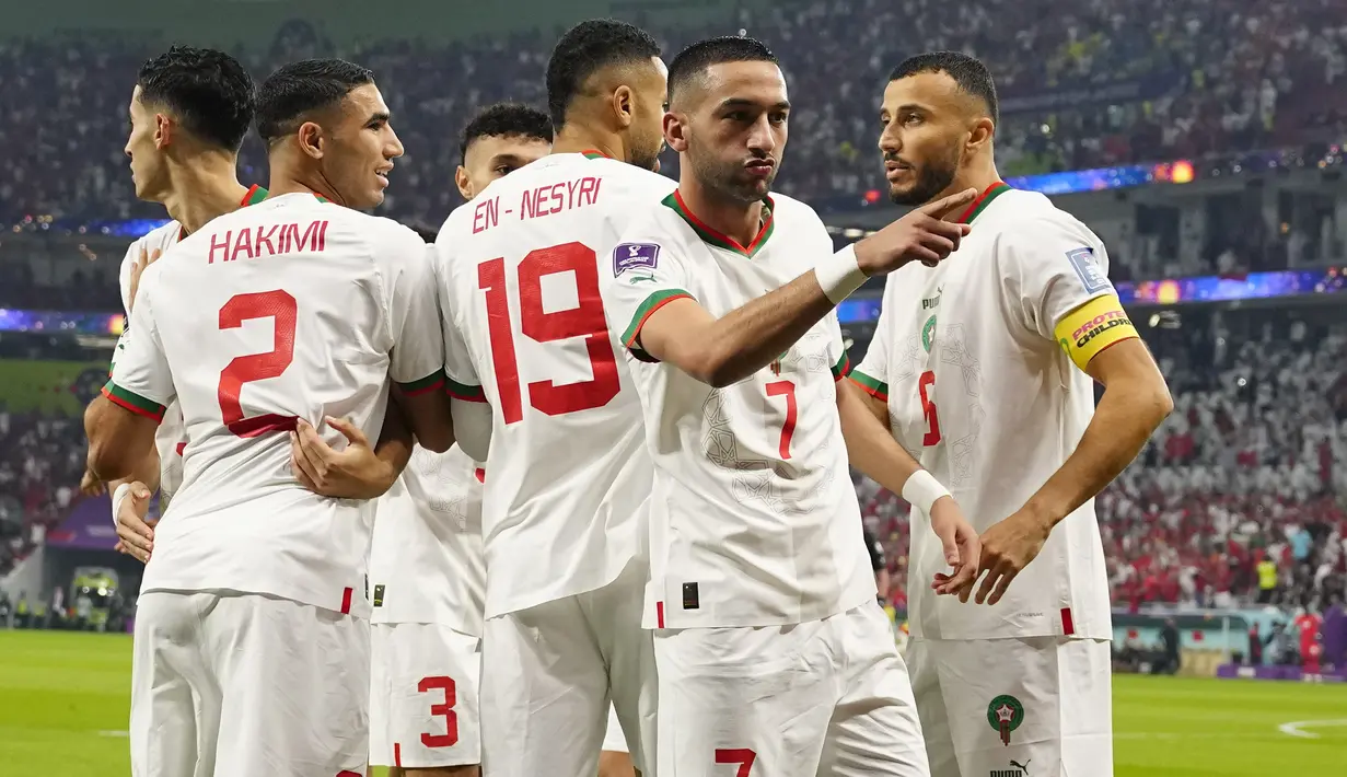 Gelandang Maroko, Hakim Ziyech (7) berselebrasi dengan dikelilingi oleh rekan satu timnya setelah mencetak gol ke gawang Kanada pada pertandingan grup F Piala Dunia 2022 di Stadion Al Thumama di Doha, Qatar, Kamis (1/12/2022). Hasil ini membuat Maroko lolos ke babak 16 besar Piala Dunia 2022 dengan status juara Grup F dengan perolehan tujuh poin. Sementara runner up jadi milik Kroasia. (AP Photo/Pavel Golovkin)