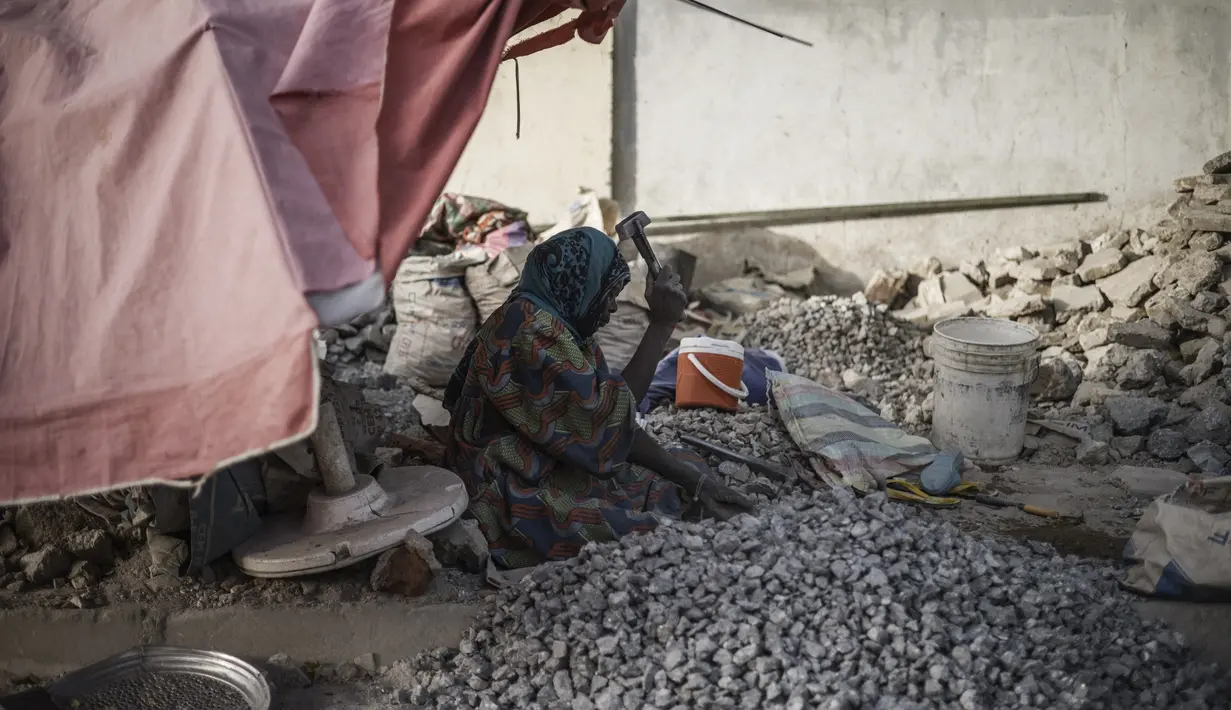 Seorang wanita menghancurkan kerikil untuk dijual sebagai pelengkap beton murah di sebuah tempat dekat Cite International des Affaires, N'Djamena, Chad, 12 April 2021. Dalam debu dan panas, wanita Chad menghancurkan kerikil untuk memenuhi kebutuhan. (MARCO LONGARI/AFP)