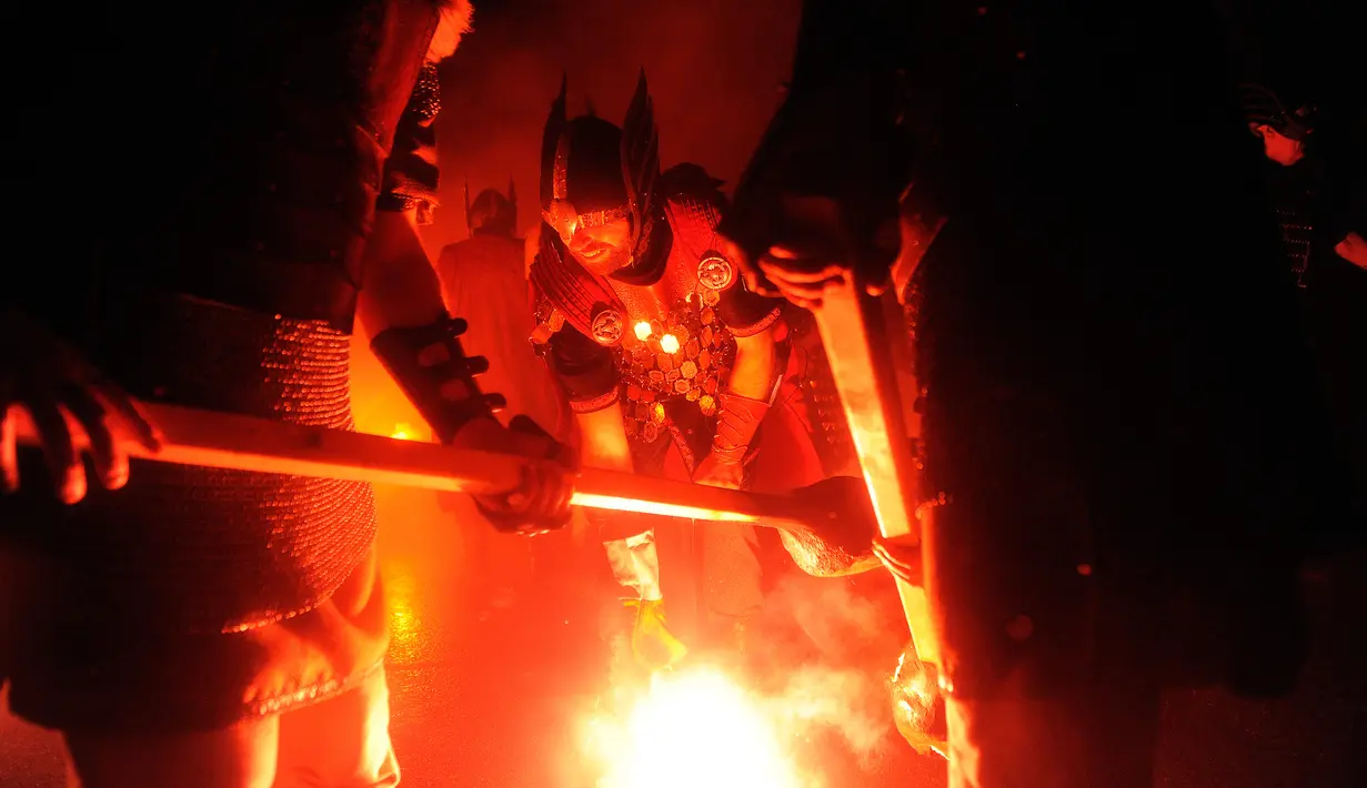 Anggota Jarl Squad menyalakan obor bersiap untuk membakar kapal perang Viking saat festival Up Helly Aa Viking di Lerwick, Kepulauan Shetland, Skotlandia (31/1). (Jane Barlow/PA via AP)