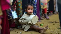 Seorang anak pengungsi muslim Rohingya menunggu bantuan makanan di kamp pengungsi Thankhali di Distrik Ukhia, Bangladesh, (12/1). Etnis Rohingya lari dari Myanmar setelah tentara memulai kampanye pemerkosaan dan pembunuhan. (Munir UZ ZAMAN/AFP)