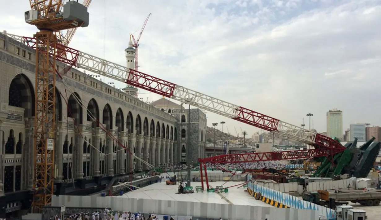 Ribuan umat muslim yang sedang menunaikan ibadah haji berjalan melintasi crane yang roboh di Masjidil  Haram, Mekah,  Arab Saudi (9/12/2015). Sebanyak 107 calon jemaah haji meninggal dunia akibat crane jatuh karena cuaca buruk. (REUTERS/ AHMED FARWAN)