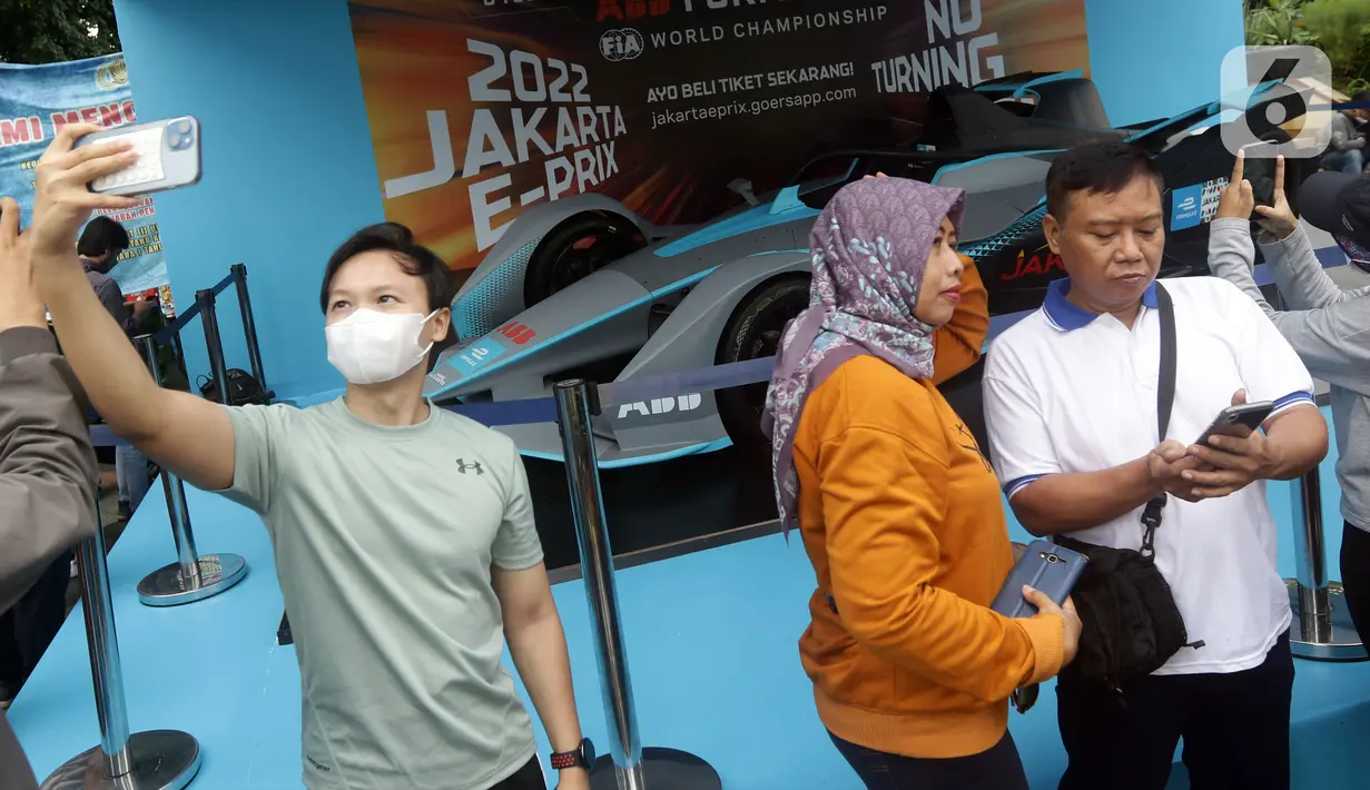 Warga berfoto dengan latar replika mobil Formula E yang dipamerkan di Kawasan Bundaran Hotel Indonesia, Jakarta, Minggu (29/5/2022). Replika mobil balap ramah lingkungan ini dipamerkan untuk mengkampanyekan perhelatan Formula E yang akan digelar 4 Juni mendatang. (Liputan6.com/Helmi Fithriansyah)