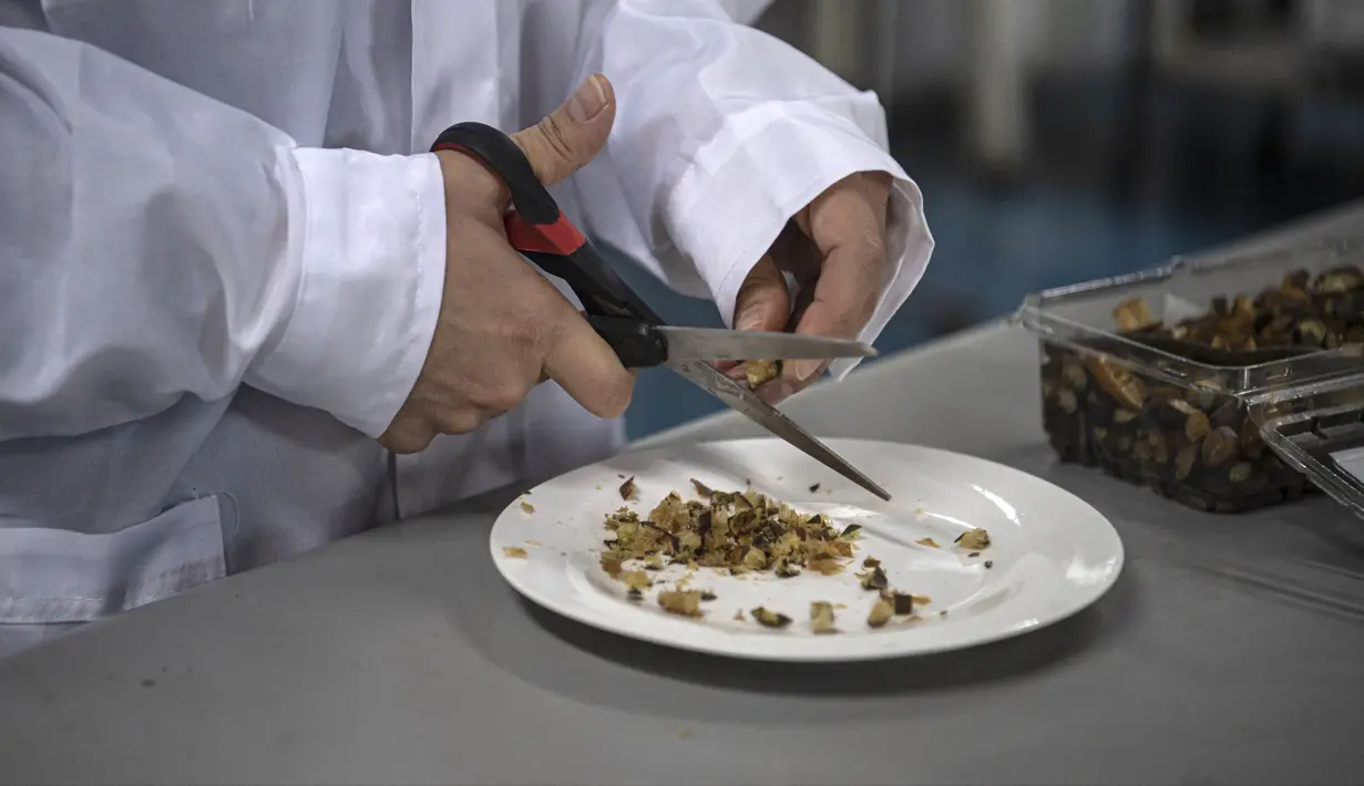 Mahasiswa teknik makanan Alonso Vasquez memotong rumput laut cochayuyo untuk diproses sebelum memasukkannya ke dalam printer 3D di Laboratorium Universitas Chile, Santiago, Chile, 17 Juni 2022. Rumput laut cochayuyo yang dikeringkan, kentang tumbuk instan, dan air panas adalah bahan yang diperlukan untuk menu bergizi makanan cetak 3D. (Martin BERNETTI/AFP)